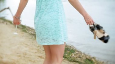 Cam şarap içme ve deniz kumlu plaj boyunca yürüyen genç güzel kadın