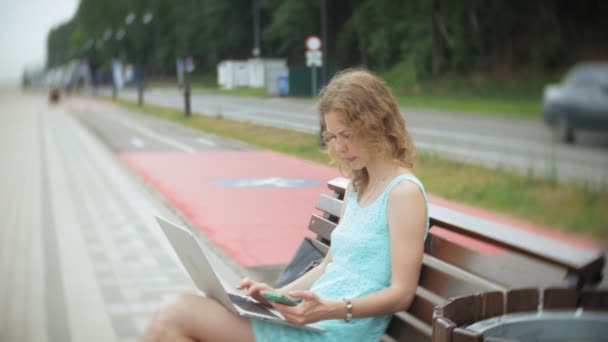 Žena sedí na lavičce na pláži na přenosném počítači — Stock video