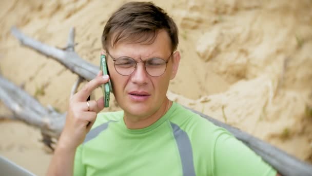 Зрілий бізнесмен розмовляє по телефону на пляжі біля моря — стокове відео