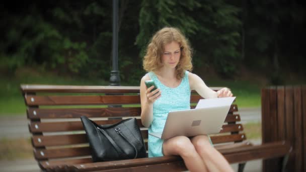 Una donna seduta su una panchina sulla spiaggia con un computer portatile — Video Stock