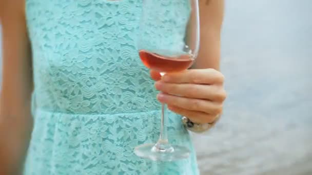 Junge schöne Frau trinkt Wein aus einem Glas und spaziert am Sandstrand des Meeres entlang — Stockvideo