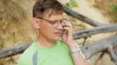 bir telefon bir güneşli gün ve içme şarap cam sahilde denizin kenarında oturan bir çağrı için malzeme çekme iş kağıtları ile bir dizüstü bilgisayarda çalışma meşgul olgun adam