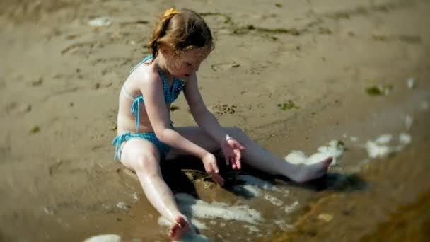 Bambina che gioca sulla spiaggia con la sabbia — Video Stock