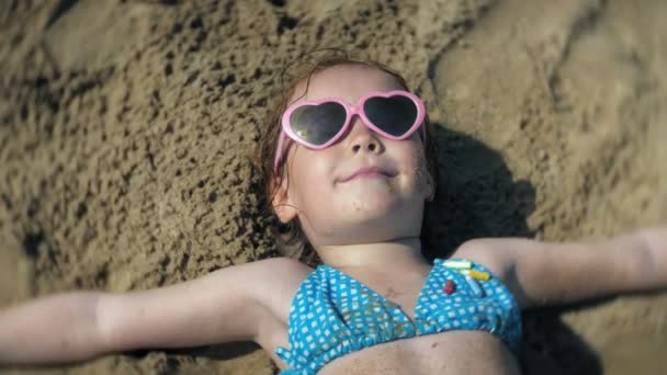 az kislány, napozásra a strandon, a napszemüveg. közeli arc