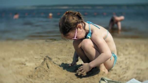 Девочка играет на пляже с песком — стоковое видео