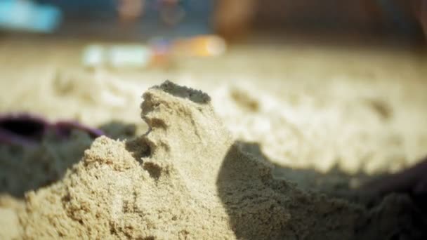 Kumlu sahilde oynarken bebeğim. bir el Close-up — Stok video