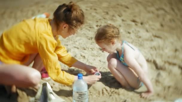 Bébé fille femelle mère jouer sur la plage avec du sable — Video