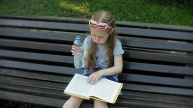 Gönüllülük a kitap, arka planını bir şehir parkı bir şehirde ahşap bir bankta oturan genç kız