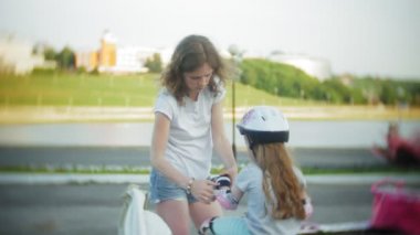 Anne ve kızı tekerlekli paten üzerinde binmek. Kız paten ve falls öğrenme. Anne kızı Silindirler binmek için öğretir