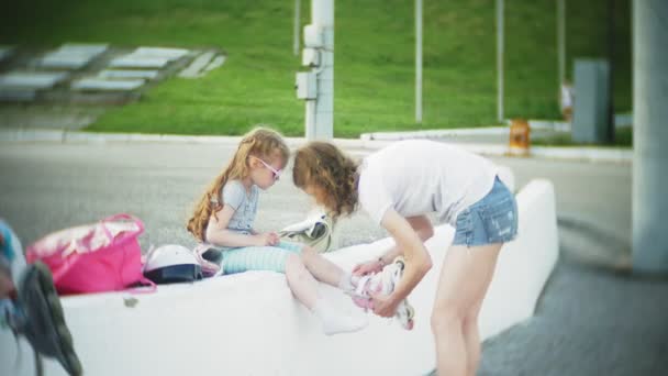 Mamá y su hija montan patines. Chica aprendiendo a patinar, y cae. Mamá enseña a su hija a montar en rodillos — Vídeos de Stock