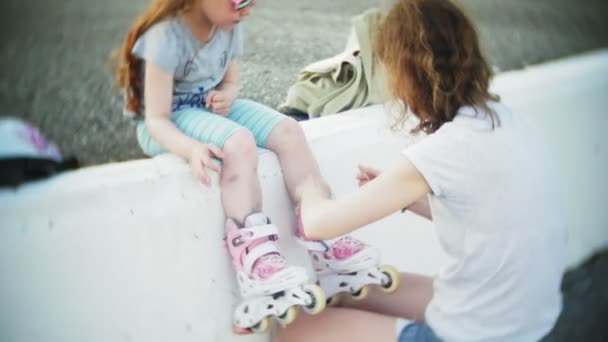 Maman et fille roulent en patins à roulettes. Une fille apprend à patiner et tombe. Maman enseigne fille à monter sur des rouleaux — Video