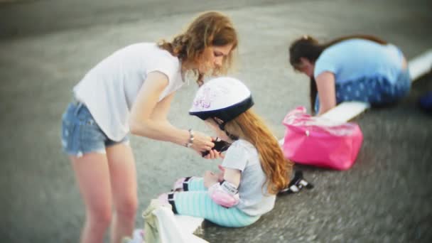 Μαμά και κόρη της βόλτα με πατίνια. Κορίτσι μάθησης για roller skate, και πτώσεις. Μαμά διδάσκει κόρη να οδηγούν σε κυλίνδρους — Αρχείο Βίντεο