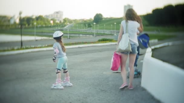 Mutter und Tochter fahren auf Rollschuhen. Mädchen lernt Rollschuhlaufen und stürzt. Mutter lehrt Tochter auf Rollen fahren — Stockvideo
