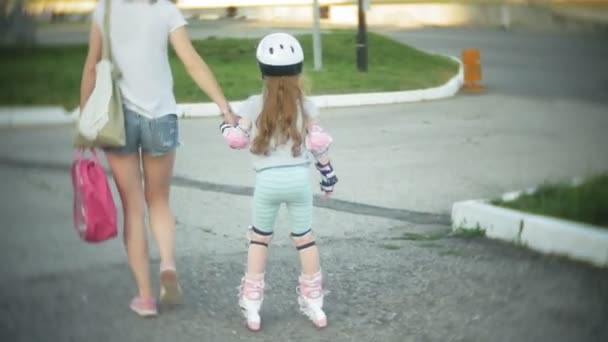 Maman et fille roulent en patins à roulettes. Une fille apprend à patiner et tombe. Maman enseigne fille à monter sur des rouleaux — Video