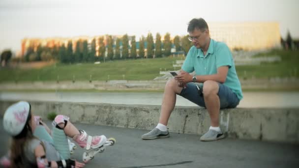 Padre e hija montan patines. Chica aprendiendo a patinar, y cae. padre enseña hija a montar en rodillos — Vídeos de Stock