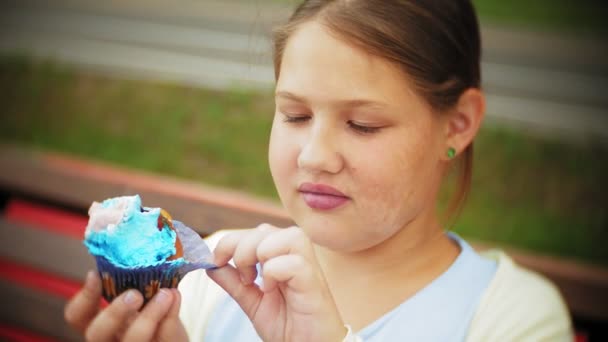 Sevimli küçük şişko kızın elleri parkta bir bankta oturmuş bir pasta yeme yakın çekim — Stok video