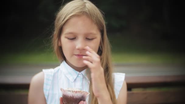 공원에서 벤치에 앉아 그녀의 손을 함께 케이크를 먹는 사랑 스러운 어린 소녀의 클로즈업 — 비디오