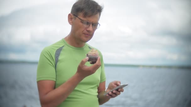 Człowiek jedzenie na ulicy, ciasto z czekoladą i śmietaną, deser, tort dziennie, żuje i zjada młody, przystojny mężczyzna — Wideo stockowe