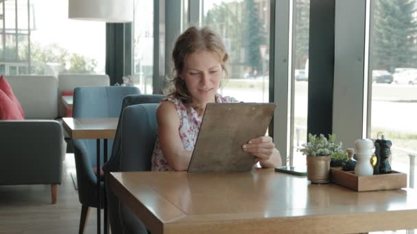 Vrouw naar op zoek is via het menu in het restaurant — Stockvideo