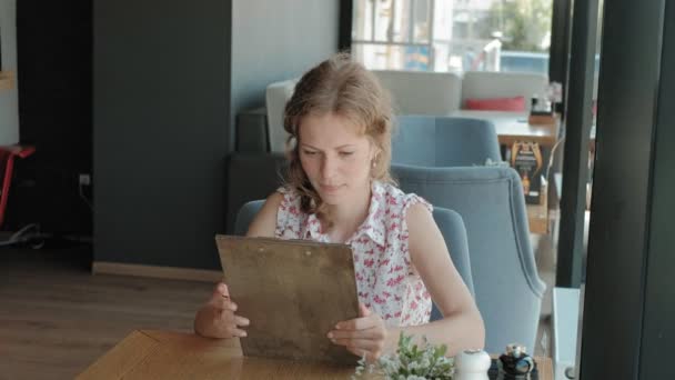 Mujer está mirando a través del menú en el restaurante — Vídeos de Stock