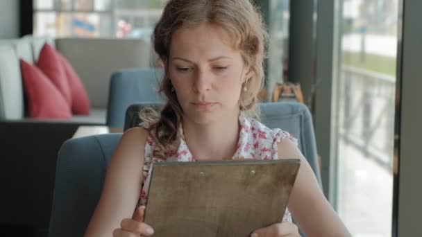 Žena se dívá přes menu v restauraci — Stock video