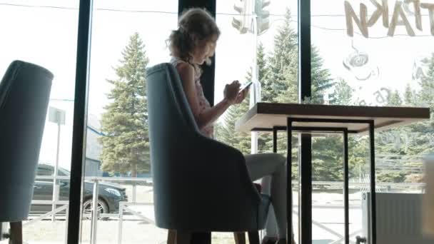 Hermosa mujer usando teléfono inteligente en la cafetería — Vídeo de stock