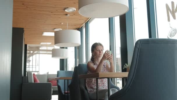 O femeie frumoasă care folosește smartphone-ul în cafenea — Videoclip de stoc
