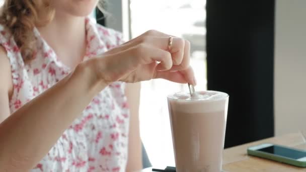 Menina feliz beber café e relaxar no café, sorrindo e olhando para o smartphone — Vídeo de Stock