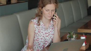 Genç iş kadını bir restoranda bir masada oturur. Kız bir laptop Internet erişimi ile yapılan, belgili tanımlık posta ve kahve içme denetler. Çok mutlu görünüyor