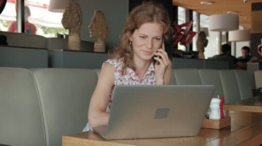 Genç iş kadını bir restoranda bir masada oturur. Kız bir laptop Internet erişimi ile yapılan, belgili tanımlık posta ve kahve içme denetler. Çok mutlu görünüyor