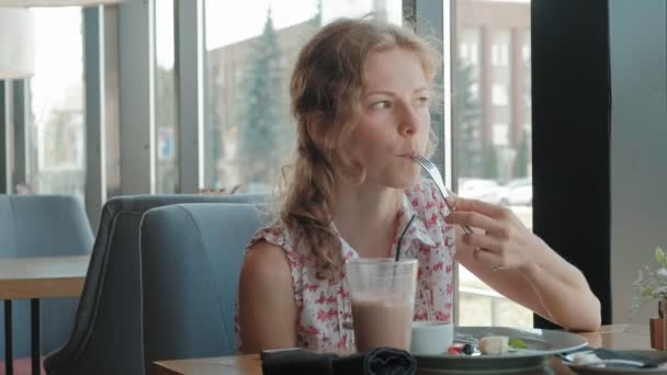 Молодая женщина ест десерт в ресторане — стоковое видео