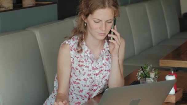 Une jeune femme d'affaires est assise à une table dans un restaurant. Elle portait un ordinateur portable avec accès à Internet, il vérifie le courrier et boire du café. Elle a l'air très heureuse — Video