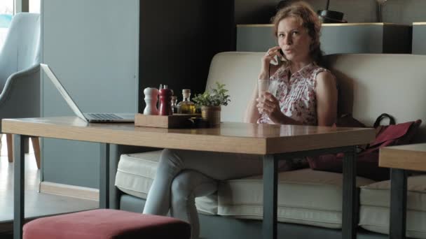 Mladí obchodních žena sedí u stolu v restauraci. Nesla přenosný počítač s přístupem k Internetu, zkontroluje pošty a pití kávy. Vypadá velmi šťastný — Stock video