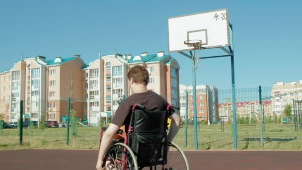 Uomo disabile gioca a basket dalla sedia a rotelle, all'aria aperta — Video Stock