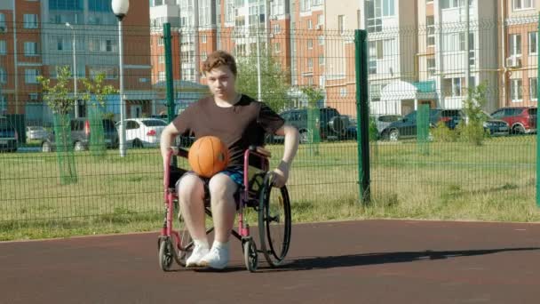 Άτομα με ειδικές ανάγκες ο άνθρωπος παίζει μπάσκετ από την αναπηρική καρέκλα του, στον ανοιχτό αέρα — Αρχείο Βίντεο