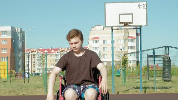 Homem com deficiência joga basquete de sua cadeira de rodas, ao ar livre — Vídeo de Stock