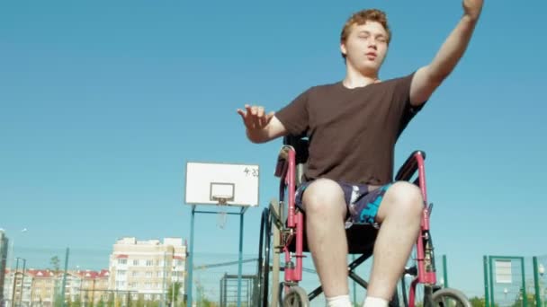 Людина з обмеженими можливостями грає в баскетбол зі свого інвалідного візка, на відкритому повітрі — стокове відео
