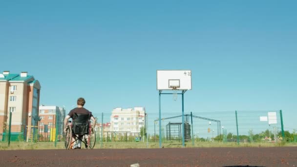 Инвалид играет в баскетбол со своего инвалидного кресла на открытом воздухе — стоковое видео