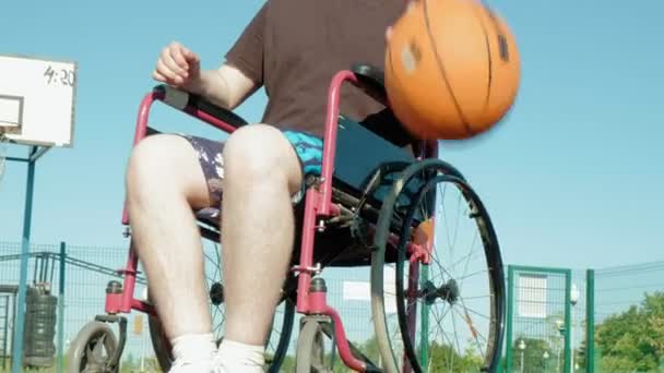 Behinderter spielt Basketball im Rollstuhl unter freiem Himmel — Stockvideo