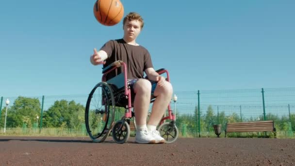 Gehandicapte man speelt basketbal van zijn rolstoel, op de open lucht — Stockvideo