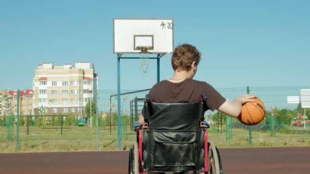 Uomo disabile gioca a basket dalla sedia a rotelle, all'aria aperta — Video Stock