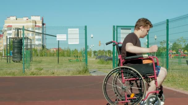 Behinderter spielt Basketball im Rollstuhl unter freiem Himmel