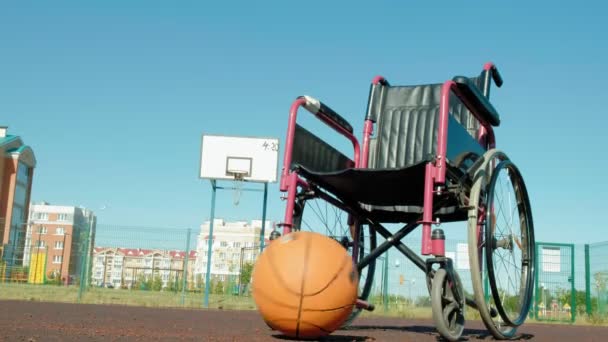 Tipo de silla de ruedas con una pelota de baloncesto en una cancha de voleibol deportiva — Vídeo de stock