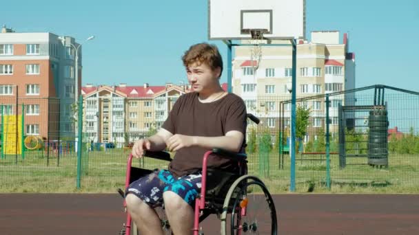 Handikappade mannen spelar basket från sin rullstol, på öppen luft, göra en insats när man spelar — Stockvideo