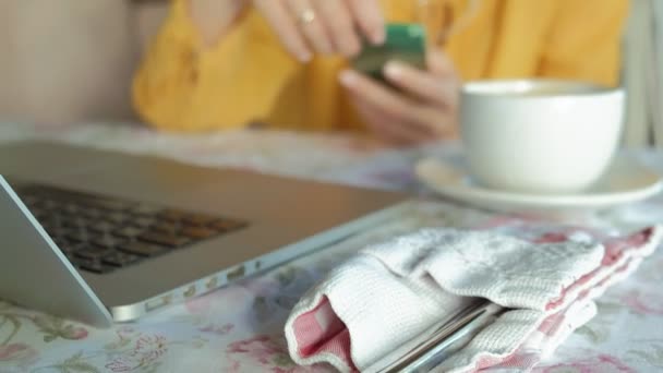 Молодая женщина с современным ноутбуком сидит в кафе и пьет кофе капучино — стоковое видео
