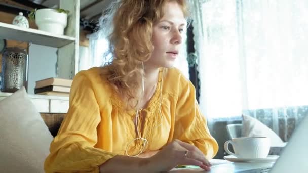 Młoda kobieta z nowoczesny laptop, siedząc w kawiarni i picie kawy cappuccino — Wideo stockowe