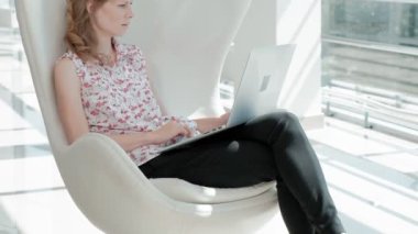 beyaz cam ofis sandalyede oturan ve dizüstü çalışma çekici işkadını