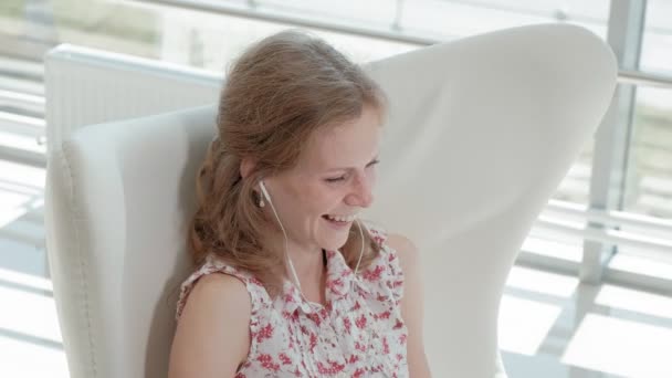 Aantrekkelijke zakenvrouw zittend op een witte stoel in glas kantoor en werken achter een laptop — Stockvideo