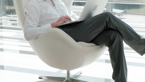 Зрілий бізнесмен сидить на білому стільці в скляному офісі і працює на ноутбуці — стокове відео