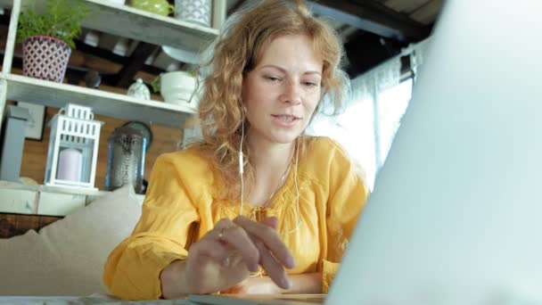 Jeune femme avec un ordinateur portable moderne assis dans un café et boire du café cappuccino — Video